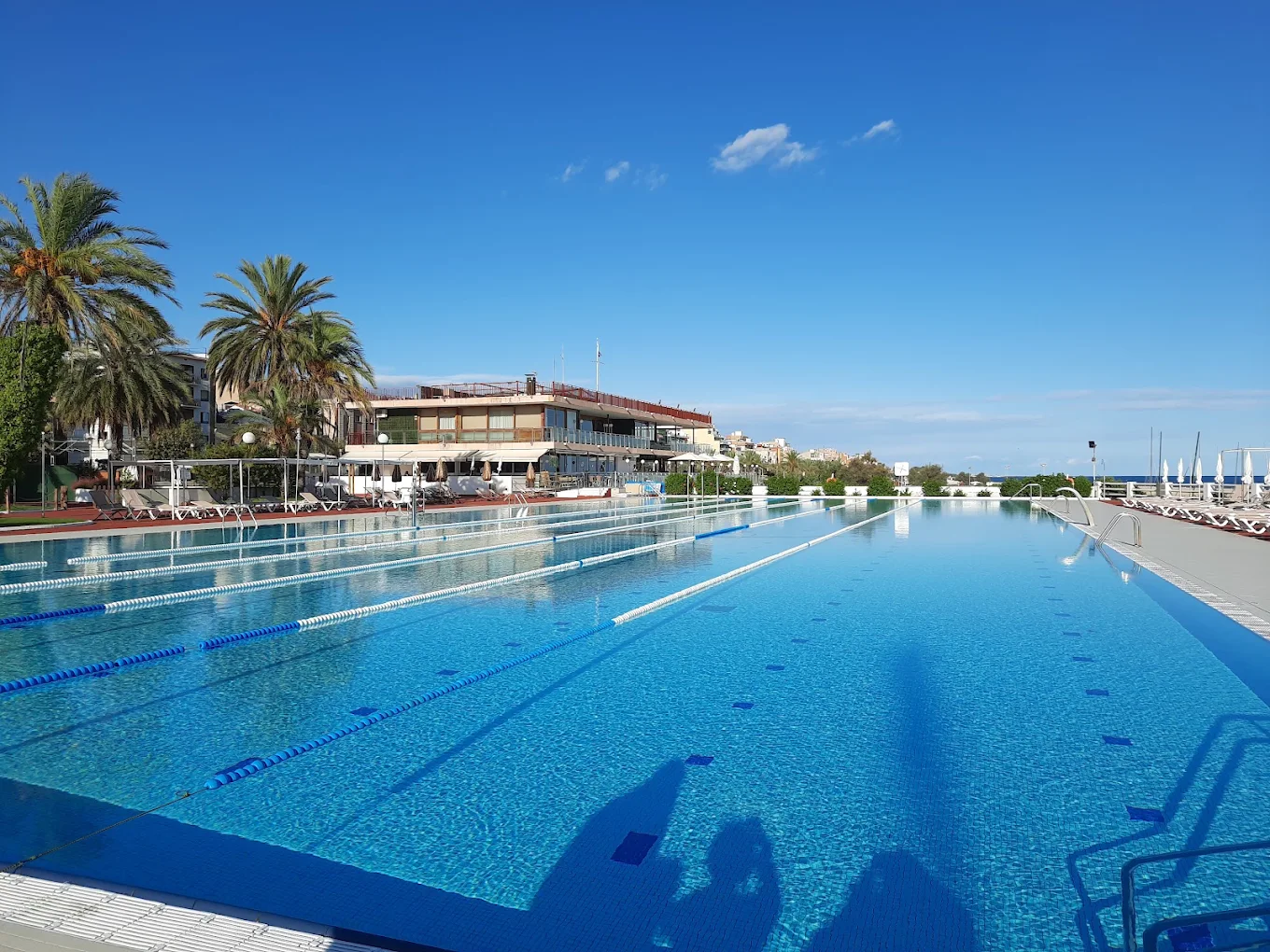 Piscina exterior del Club Nàutic El Masnou amb l’edifici social al fons